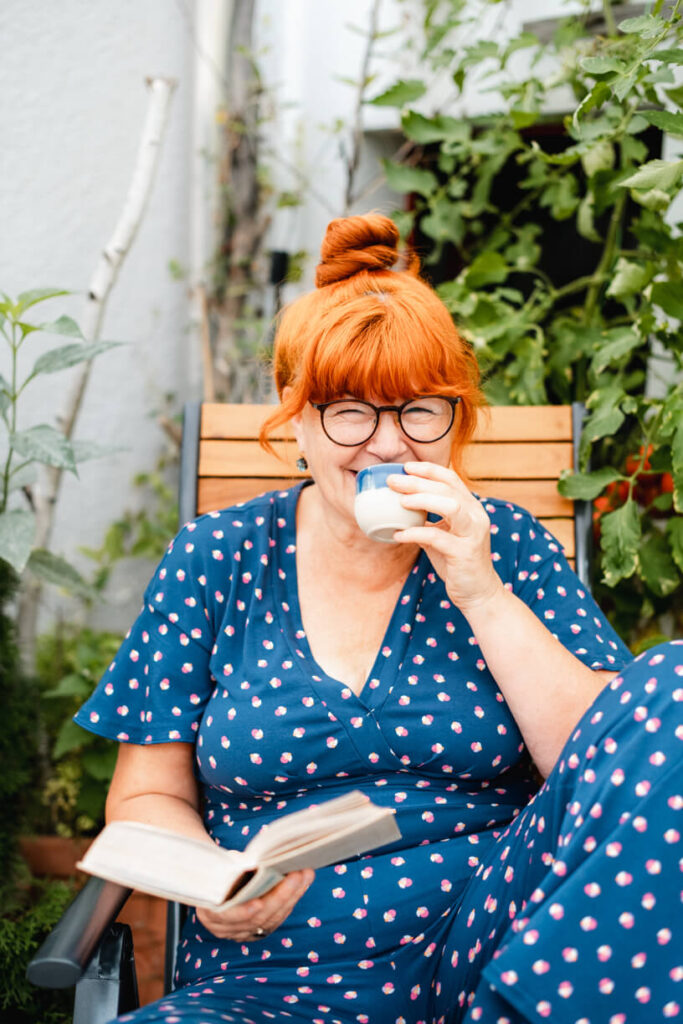 Silke Friedmann sitzt, liest und trinkt aus einem Espressobecher